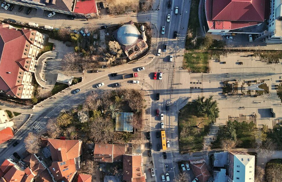 A high-angle drone shot capturing Pristina's urban landscape with busy streets and traffic.
